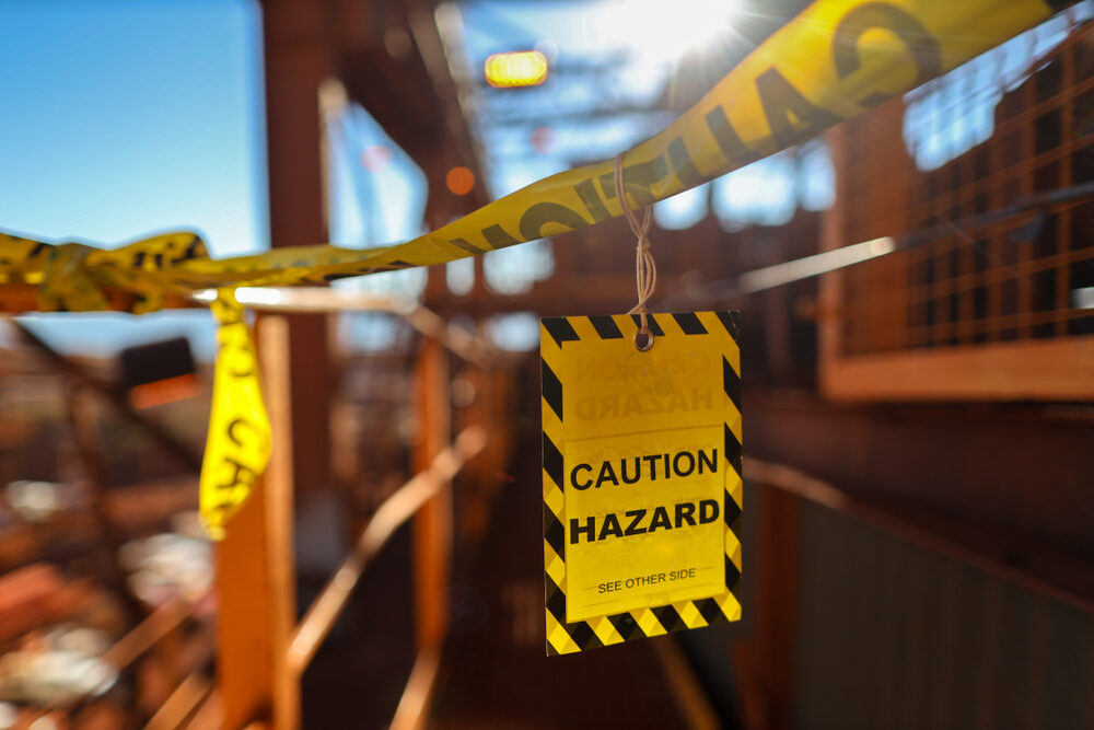 Yellow caution/hazard sign tag on caution tape at the entry of construction site