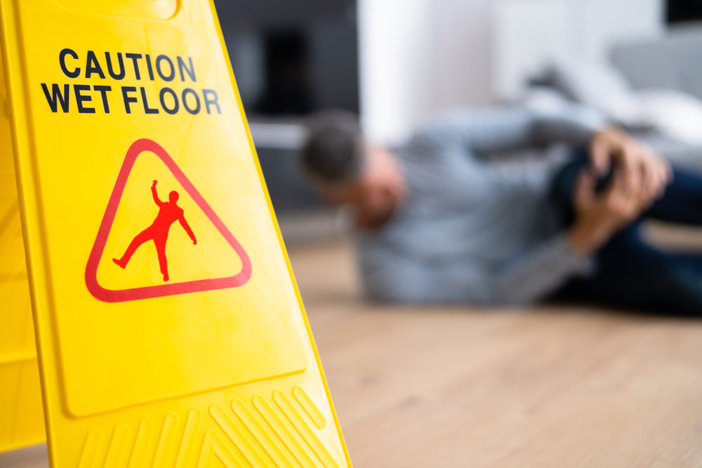 caution sign with blurred man after slip and fall