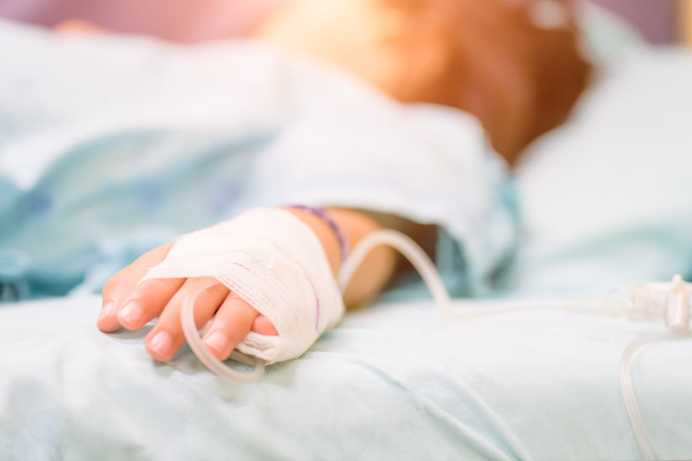 Closeup kid hand sleeps on a bed in hospital with saline intravenous