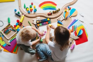 young children painting and playing with educational toys on white paper coveredfloor 