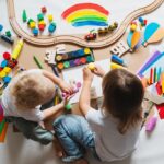 young children painting and playing with educational toys on white paper coveredfloor 