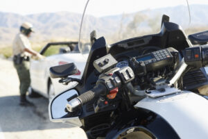 california highway patrol motorcycle officer stopping a white convertible