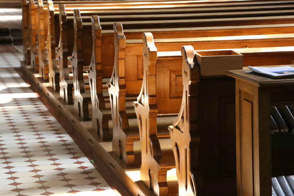 sunlight shining on church pews along tiled walkway 