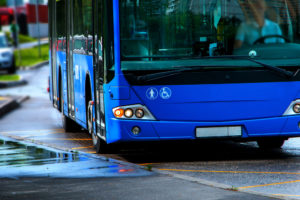 A blue accessible city bus pulls up to the curb