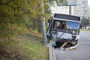 A city bus with extensive damage sits on the road