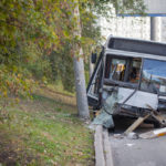 A city bus with extensive damage sits on the road