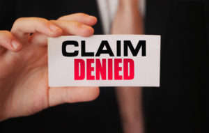 Businessman shows a card with text Claim Denied 