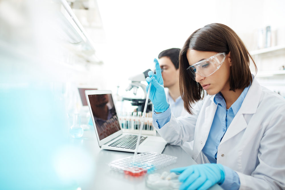 A lab technicion extracts a sample from a tray in a laboratory