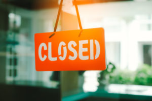 A sign reading "CLOSED" hangs against a blurred background