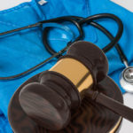 Medical scrubs with a stethoscope and gavel against a white background