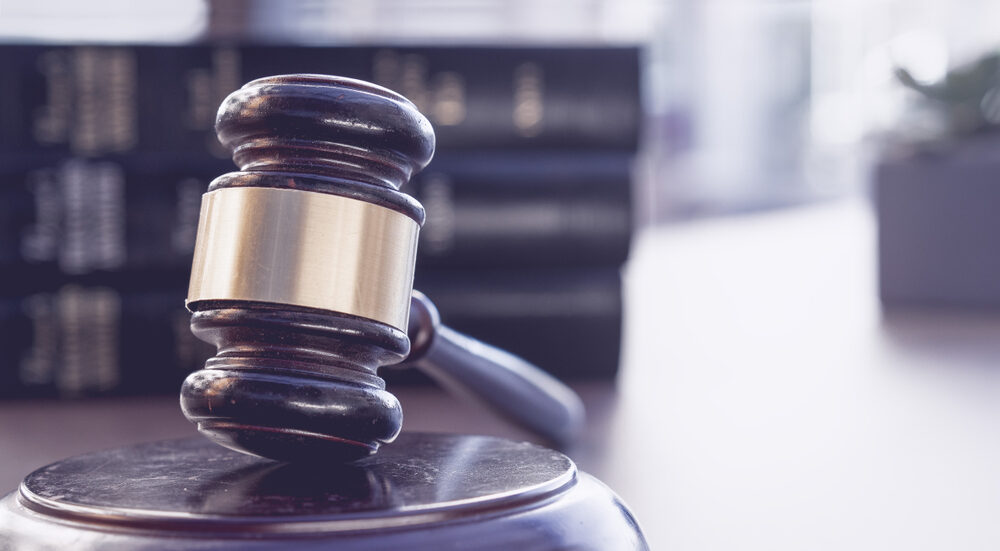 a closeup of a wooden gavel on a desk with blurred law books in background