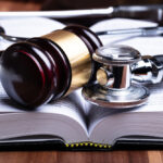 closeup of a gavel and stethoscope laying on an open book