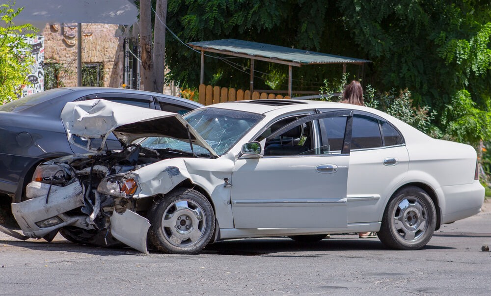 white and blue car damaged after car crash in the roadway