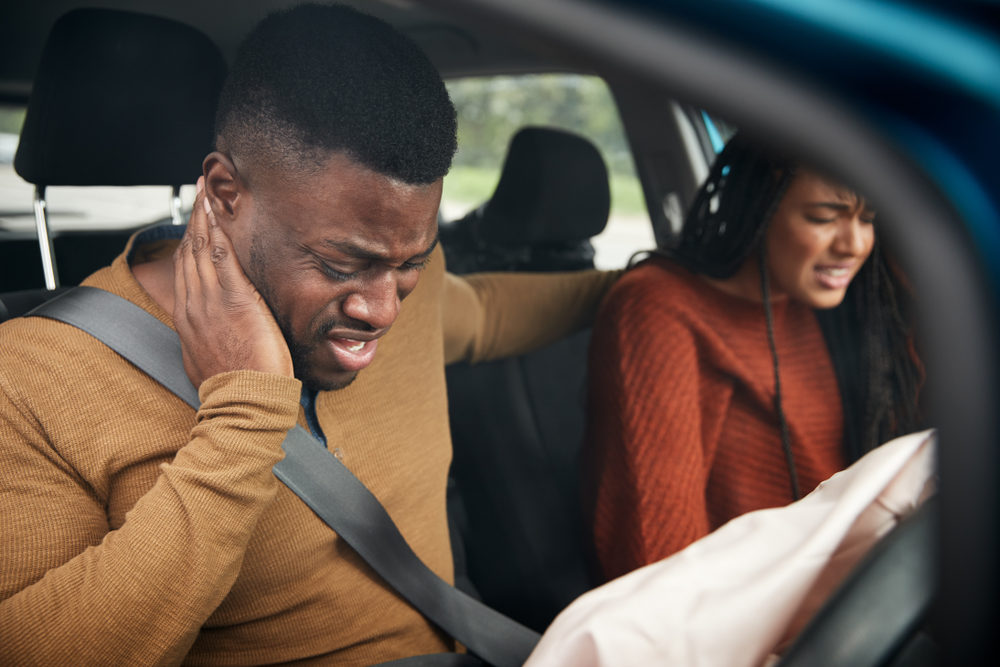 Black couple involved in a car accident with male driver holding his neck