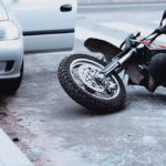 Motorcycle lying on the road and car standing with open door after a collision