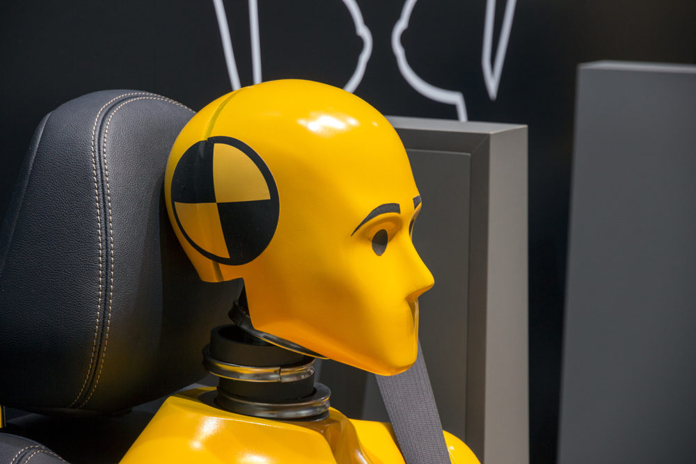 Yellow crash test dummy in a car seat.