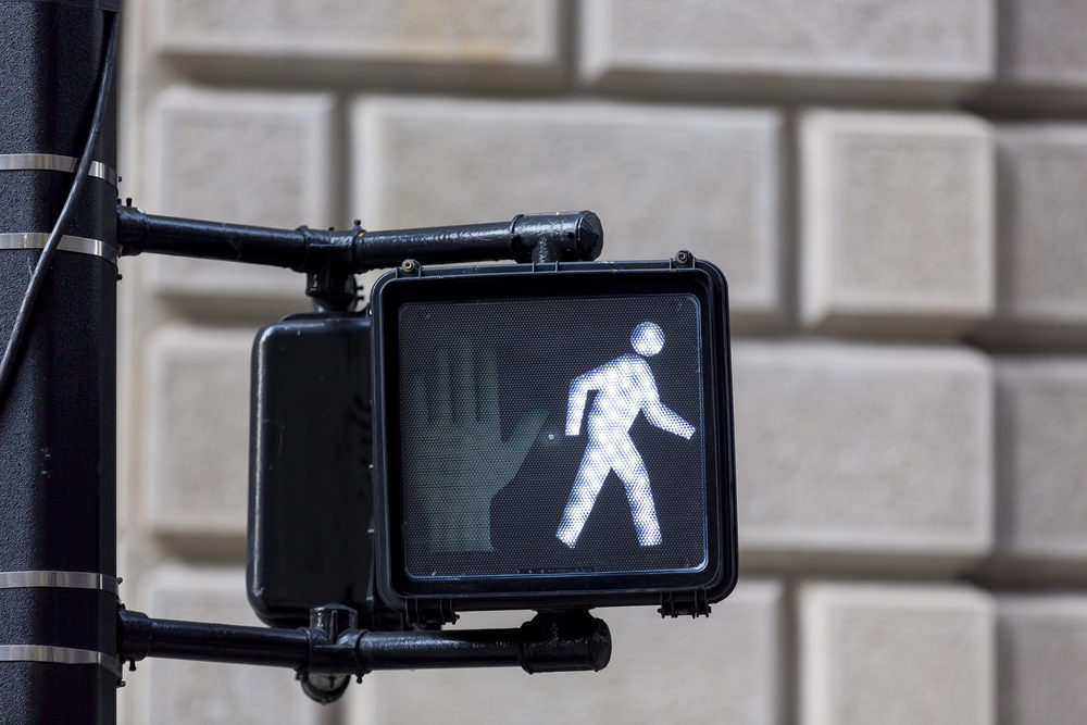 crosswalk sign with pedestrian walk light showing at intersection closeup