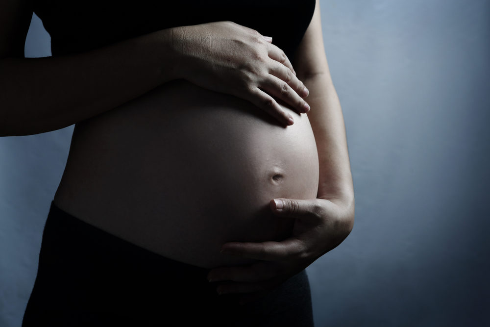 closeup of a pregnant woman's belly with dark lighting