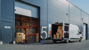 white van with packages in the back with the doors open outside of a warehouse