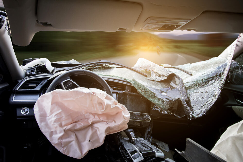 interior view of a crashed car with windshield busted out and airbags deployed