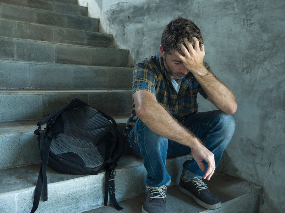 depressed college student man sitting on staircase desperate victim of harassment suffering bullying and abuse