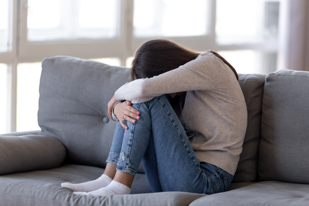 Depressed teen girl sitting on couch