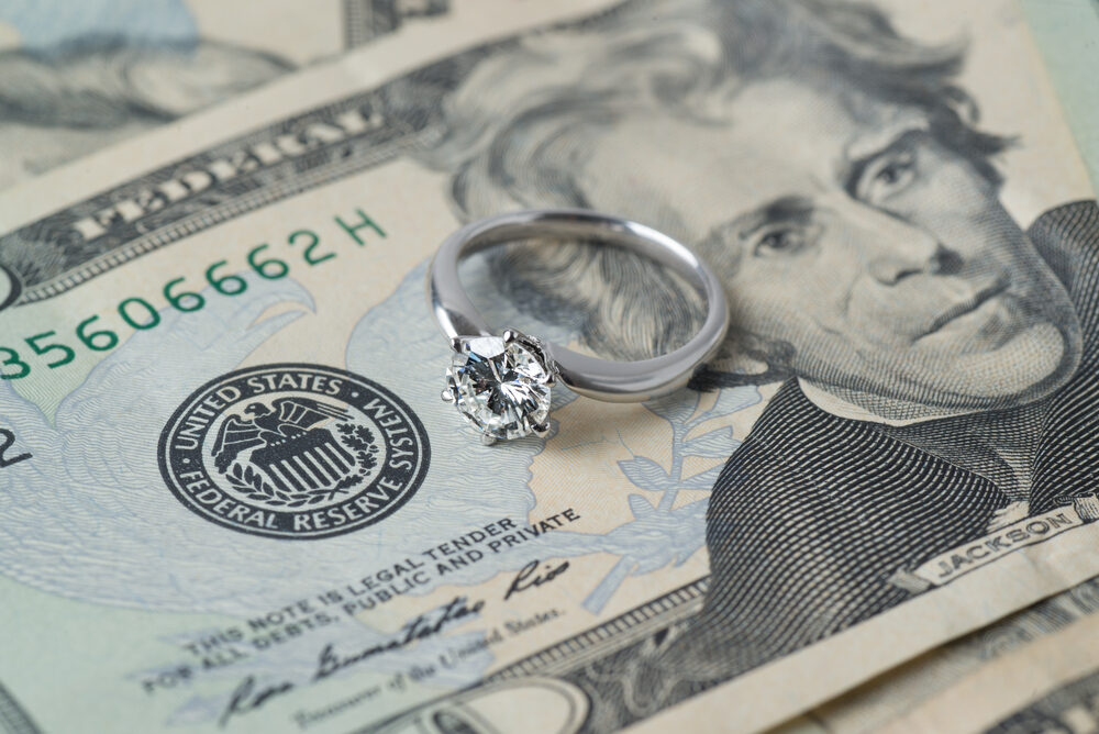 diamond engagement ring on stack of us currency