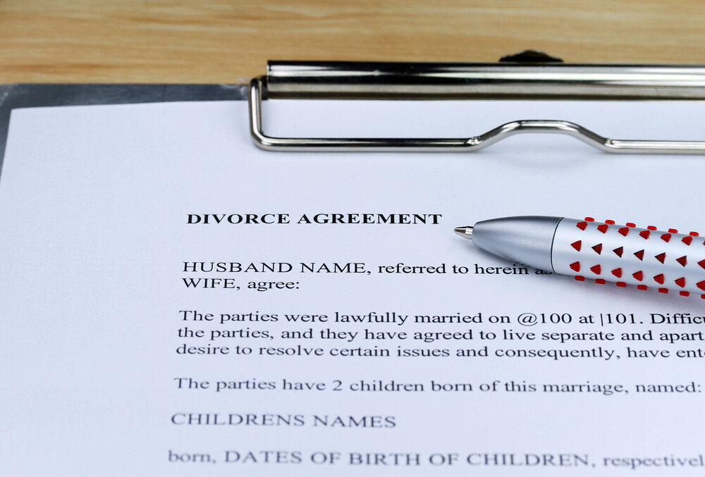 A Divorce agreement contract on a clipboard at a lawyers desk along with a ball point pen