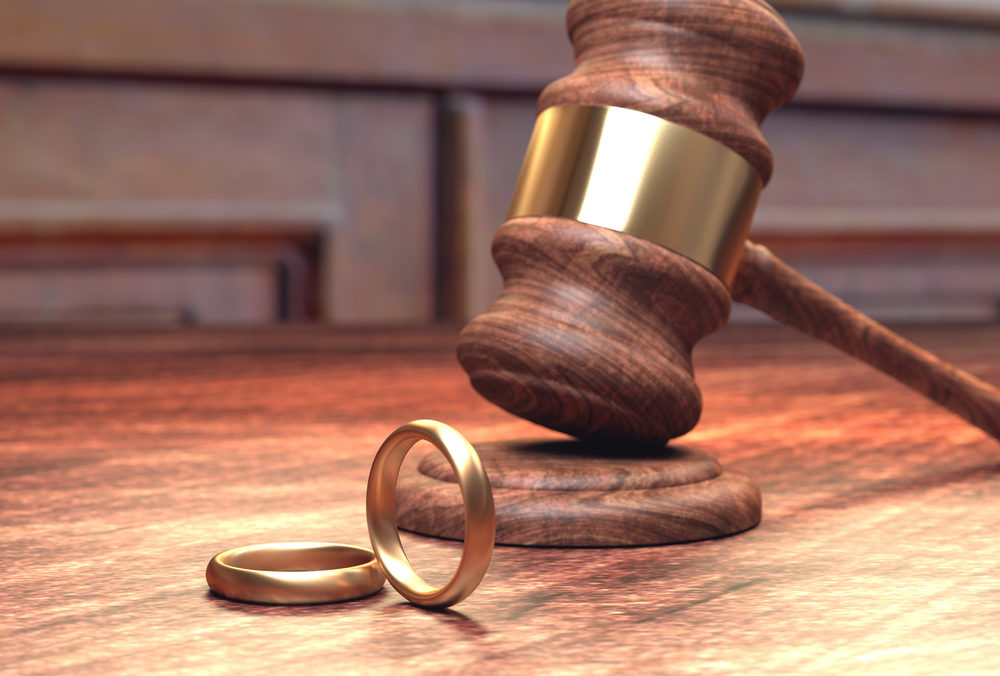 A gavel on a banger with two gold wedding bands (3d rendering)