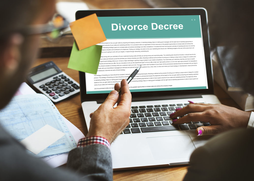A  man and woman working at a laptop on a divorce decree  