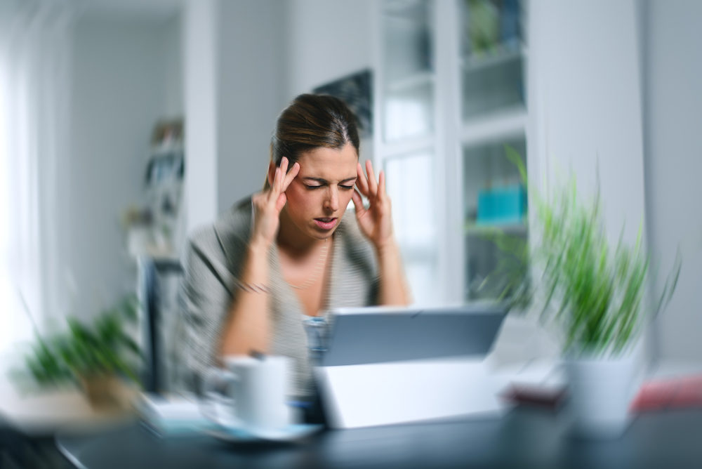 A woman holds her head in anguish, with a spinning blurred background