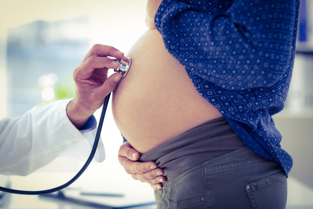  image of doctor using stethoscope white examining pregnant woman in clinic