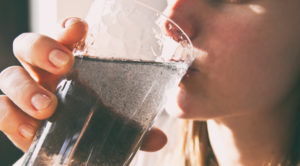 woman is drinking dirty water from the glass cup