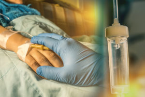 cancer patients hand being comforted by doctor gloved hand with transfusion drip in forefront
