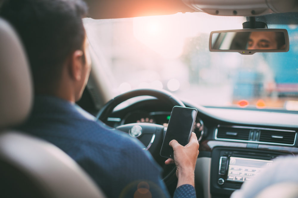 Back view of man using mobile phone at the car