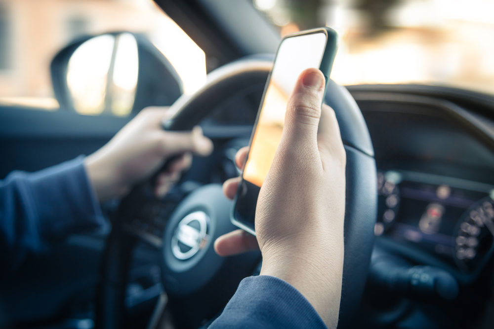 man reading messages holding a cell phone while driving.