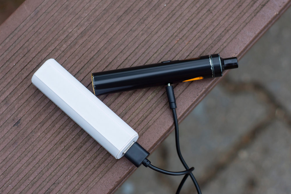 Power bank and charges an electronic cigarette on a wooden bench