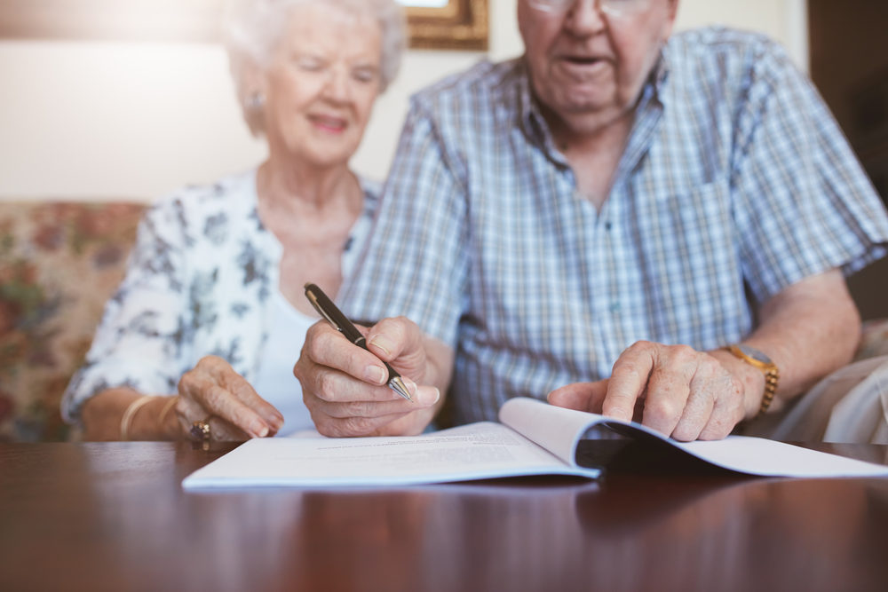 An elderly couple reviewing and signing documents