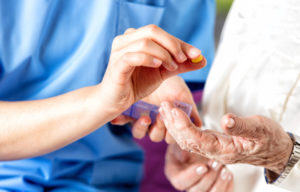 Hand of young nurse giving medical pill to elderly woman.