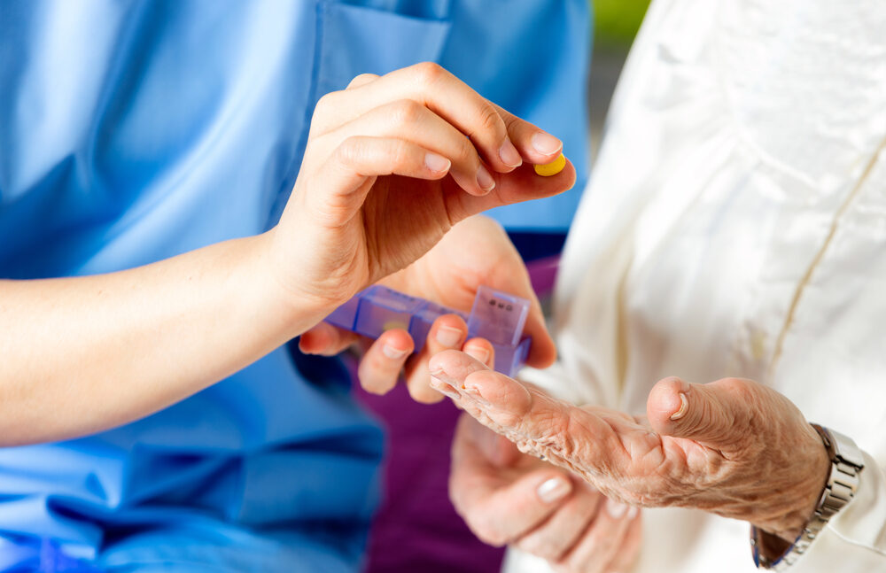 nurse giving a pill to an elderly patient in a nursing home