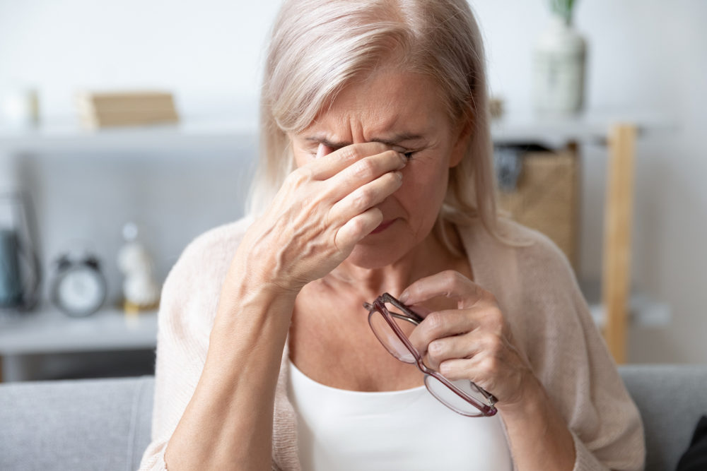 Elderly woman crying wipes tears with hands feels unhappy, bad news