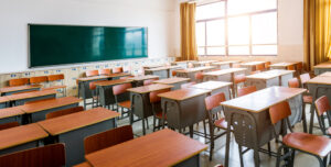 Empty classroom with desks, chairs and chalkboard.