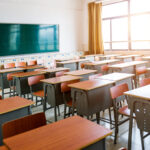 Empty classroom with desks, chairs and chalkboard.