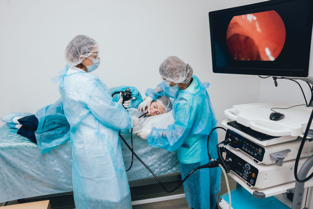 doctors performing endoscopy on patient in hospital with screen