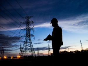 silhouette man of engineers standing at electricity station over Blurred electricity power