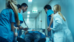  Doctors, Nurses and Surgeons Move Seriously Injured Patient Lying on a Stretcher Through Hospital Corridors.