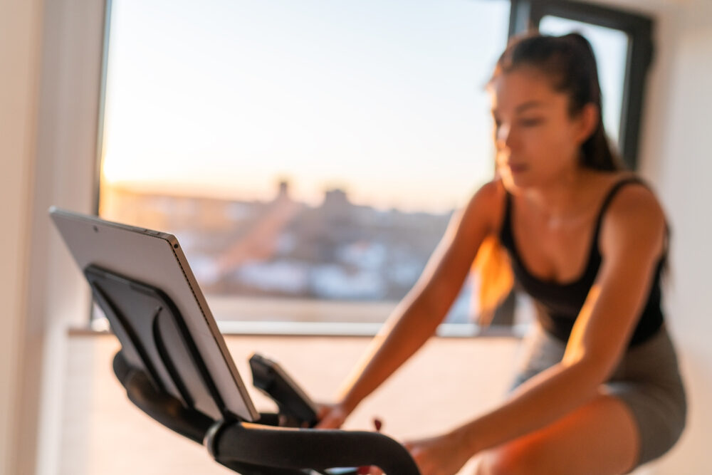 Home fitness fit woman exercising on smart stationary bike at home gym