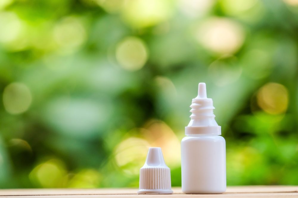 eye drop bottle with lid on table with blurred nature background