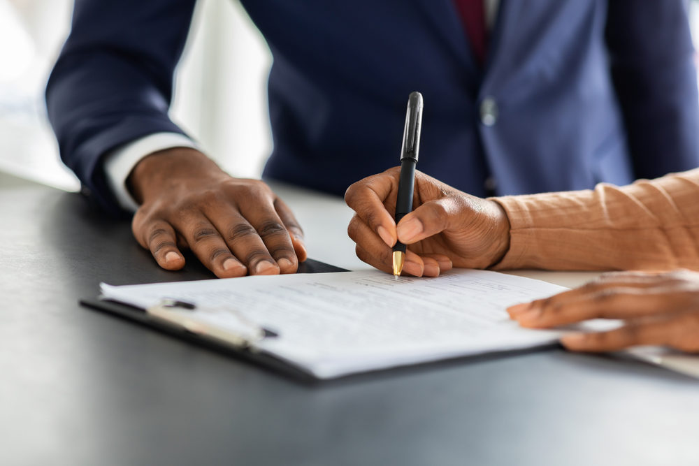 african american female signing a contract with an attorney