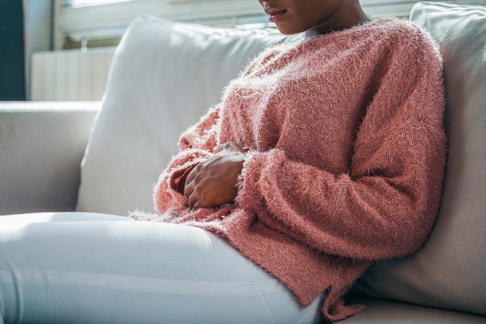 african american woman holding her stomach due to abdominal pain